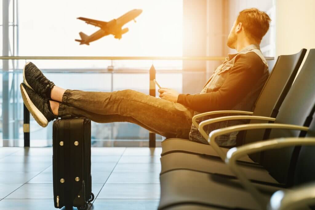 Man sitting at the airport, staring out window as he watches plane take off.