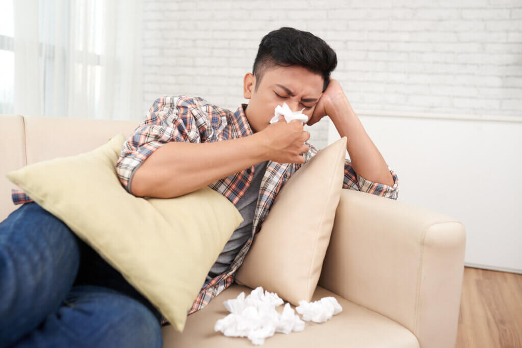 Young asian man suffering runny nose having medical leave staying home